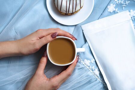 Template of paper ecological bag for storing coffee, tea on the background of a female dress and hands with cappuccino. Vacuum packaging for christmas and new year presentの写真素材