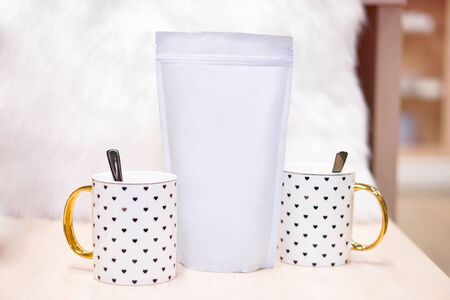 Template of paper ecological bag for storing coffee, tea on the background of cups and utensils. Vacuum packaging for christmas and new year presentの写真素材