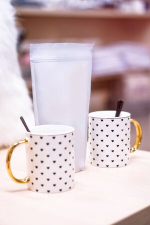 Template of paper ecological bag for storing coffee, tea on the background of cups and utensils. Vacuum packaging for christmas and new year presentの写真素材