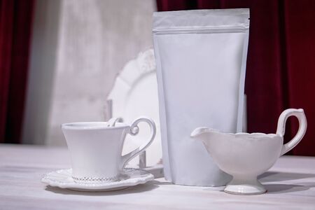 Template of paper ecological bag for storing coffee, tea on the background of cups and utensils. Vacuum packaging for christmas and new year presentの写真素材