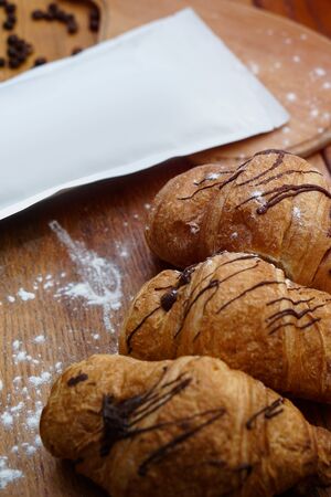 Mocap with croissants on a wooden board background for your logo or brand. packaging of coffee, tea as a template for design. Box with a clean side.の写真素材
