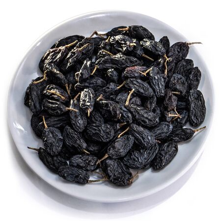 Dark raisins on a white isolated background. Food brown-blue grapes delicious for your design for the site. kitchen themeの写真素材