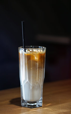 Coffee drink in a glass cup. Latte on a dark background in a cafe. Business stock photo for design