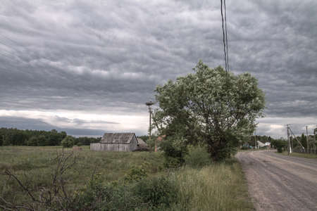 Beautiful, and epic thunderclouds in a village with a road to the unknown. The sky as the forerunner of a hurricane in Europe. Stock photo clouds for designの写真素材