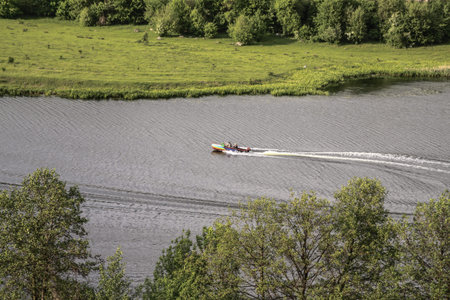 Top view of the river with a fast-moving motorboat with tourists in a nature reserve. Fishermen sail...