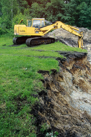 An excavator digs a large trench for building a house. A tractor digs a large lake that is already...