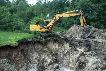 An excavator digs a large trench for building a house. A tractor digs a large lake that is already...
