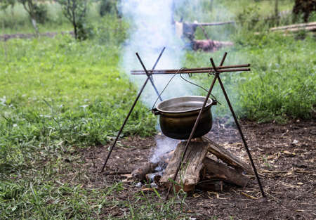 Bonfire and bowler on a background of nature. Summer camping in the park or outdoorsの写真素材