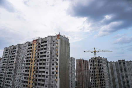 Multi-stage construction during the construction process with a yellow crane. Industrial background for design.の写真素材