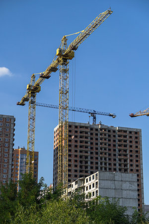 Multi-stage construction during the construction process with a yellow crane. Industrial background for design.の写真素材