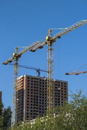 Multi-stage construction during the construction process with a yellow crane. Industrial background for design.の写真素材