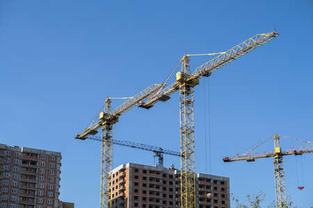 Multi-stage construction during the construction process with a yellow crane. Industrial background for design.の写真素材