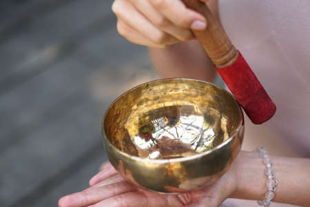 Meditation with vibrations from the bowl in the lotus position. Nature yoga theme hands and bronze utensils. soul music on an instrumentの写真素材