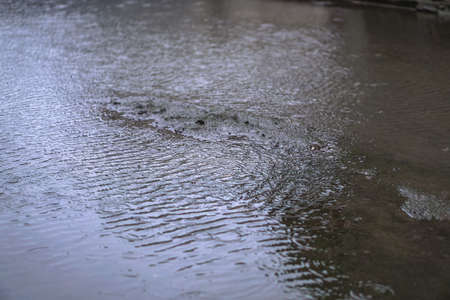 Road in poor condition is flooded with rain. Downpour and streams of water on the asphalt. Autumn backgroundの写真素材