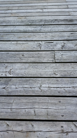Silvery worn wood planks run horizonally as a background with character. Top planks recede into distance.の写真素材
