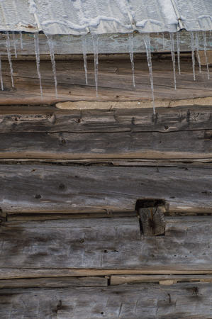 Wintertime snowy old pioneer log cabin barn with icicles. Sunny day.  closeupの写真素材