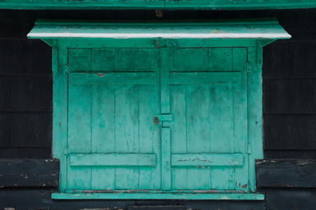 Grungy faded green mildewy shuuters with snow on a waterfront cottage.  Locked on a black cottage in winterの写真素材