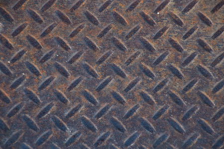 Closeup landscape of a distressed, mottled, gungy industrial diamondplate, chequerplate rusty metal background texture with diamond grip pattern perfect for wallpaper for the construction, heavy equipment and industrial companies.の写真素材
