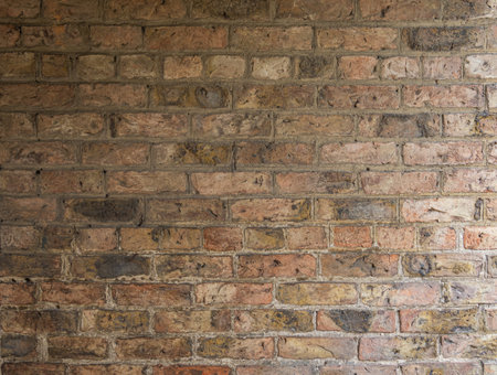 Darkened aged brick wall with uneven coloration and worn industrial character.