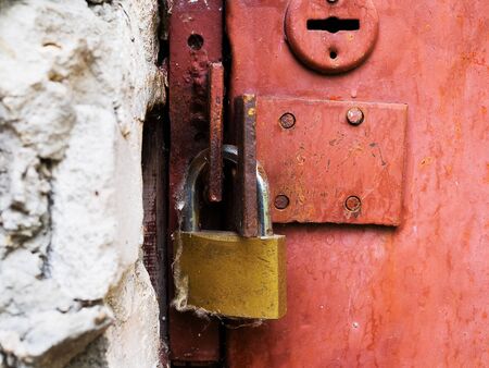 The old red metal door is closed on the padlock.の写真素材