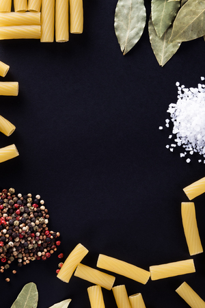 Pasta and spices on a black background, copy space, vertical.の写真素材