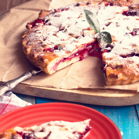 Homemade Cherry-apple pie with sugar on a paper. Slice of pie on a red plate. Square toned  photo.の写真素材
