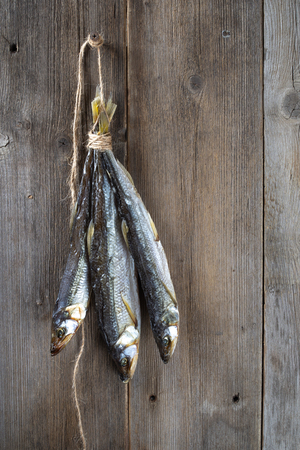 A bunch of dried fish hanging on a wooden background. Vertical.の写真素材