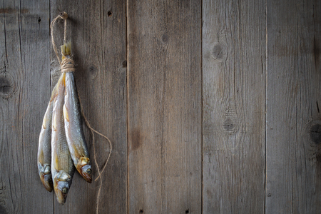 A bunch of dried fish hanging on a wooden background. Copy space.の写真素材