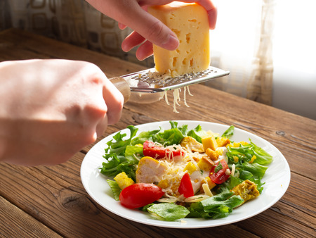Adding cheese to Cesar salad. の写真素材