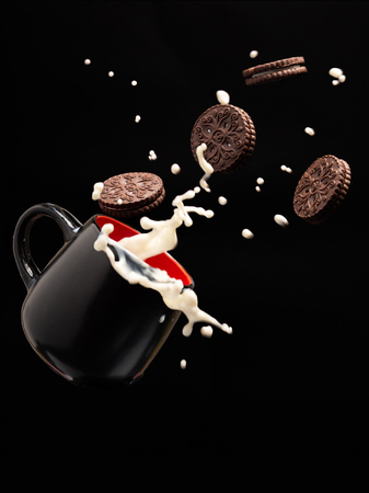 flying chocolate cookies and splashes of milkの写真素材