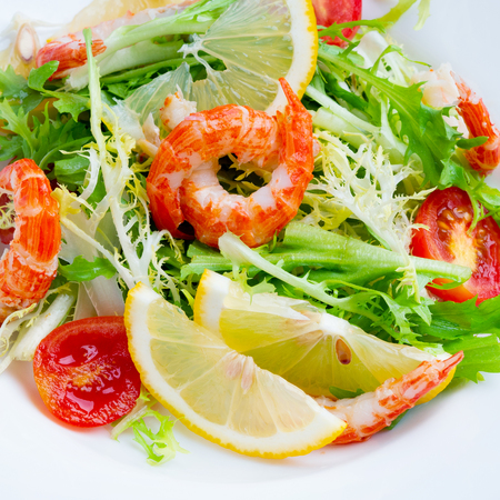 Salad with rocket salad, tomato and shrimp on a white plate. Close-upの写真素材