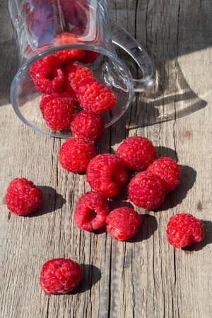 Raspberry is scattered on a wooden surface, verticalの写真素材