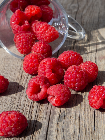 Raspberry is scattered on a wooden surface, verticalの写真素材