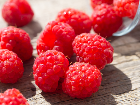 Raspberry is scattered on a wooden surface, verticalの写真素材