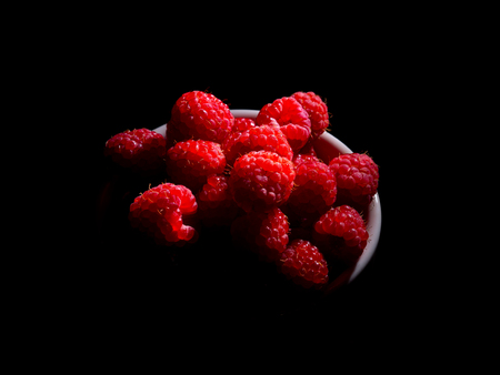Raspberry in a mug on a black backgroundの写真素材