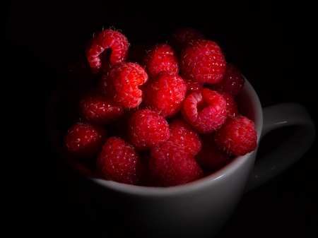 Raspberry in a mug on a black backgroundの写真素材
