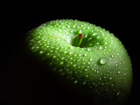 Green ripe apple with water droplets on a dark background, closeupの写真素材