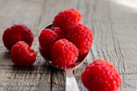 Ripe raspberries on a spoon on a wooden background.の写真素材