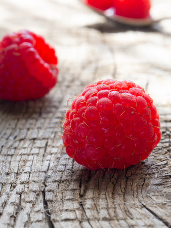 Raspberry berries are large on a wooden surface, verticalの写真素材
