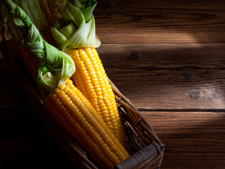 Corn in a basket on a brown boardsの写真素材