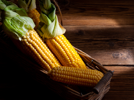 Corn in a basket on a brown boardsの写真素材