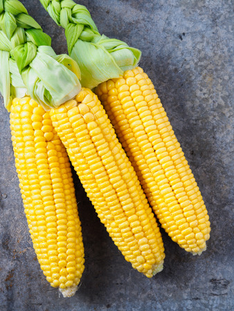 Fresh juicy corn on a tin surface, vertical.の写真素材