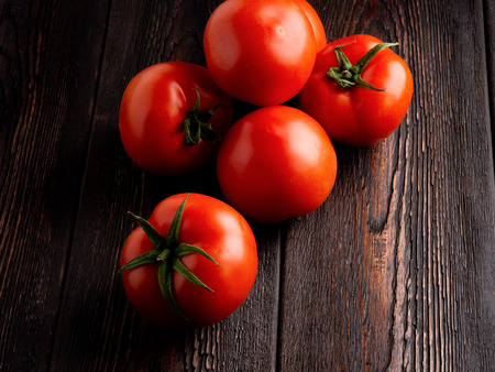 Tomatoes on a dark brown wooden background.の写真素材