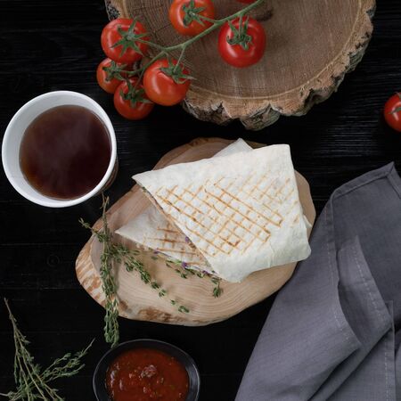 Tasty juicy shawarma in a cut. Near a branch of tomatoes and thyme. Top of view.の写真素材