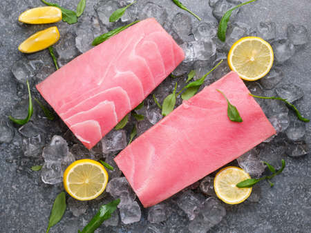 Fresh tuna fillet on ice with lemon and basil. View from above. Tin background.の写真素材