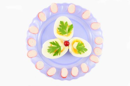 Cooked boiled eggs with sauce, decorated with parsley,  cranberry and crab sticksの写真素材