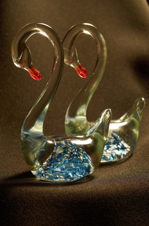 A pair of transparent glass figurines of swans on a black backgroundの写真素材