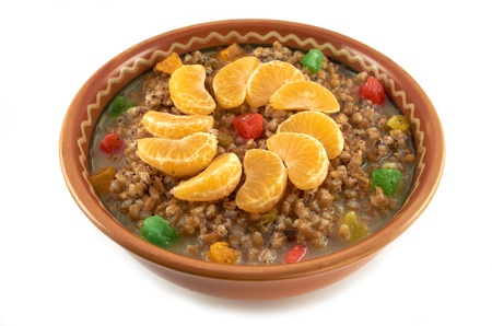 Sweet wheat porridge with dried fruit, lobules tangerine and honey in a clay bowlの写真素材