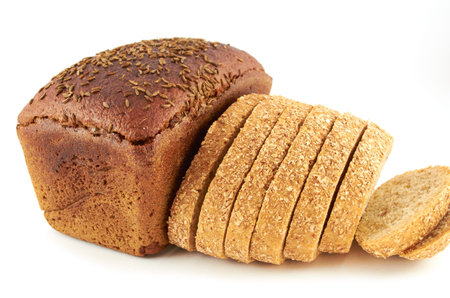A loaf of rye bread topped with coriander seeds and sliced wheat bread with bran