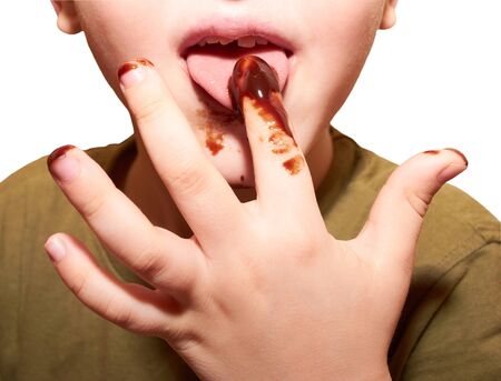 Child licks a chocolate glaze with your fingerの写真素材